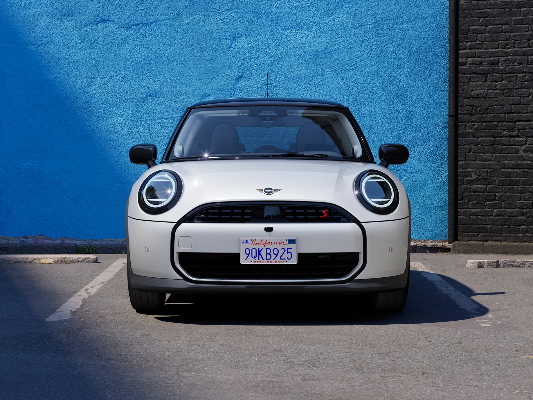 Widok z przodu na parkujące MINI Cooper w kolorze Nanuq White z czarnym dachem.