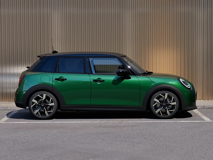 Widok z boku na zaparkowane 5-drzwiowe MINI Cooper w kolorze British Racing Green z czarnym dachem.