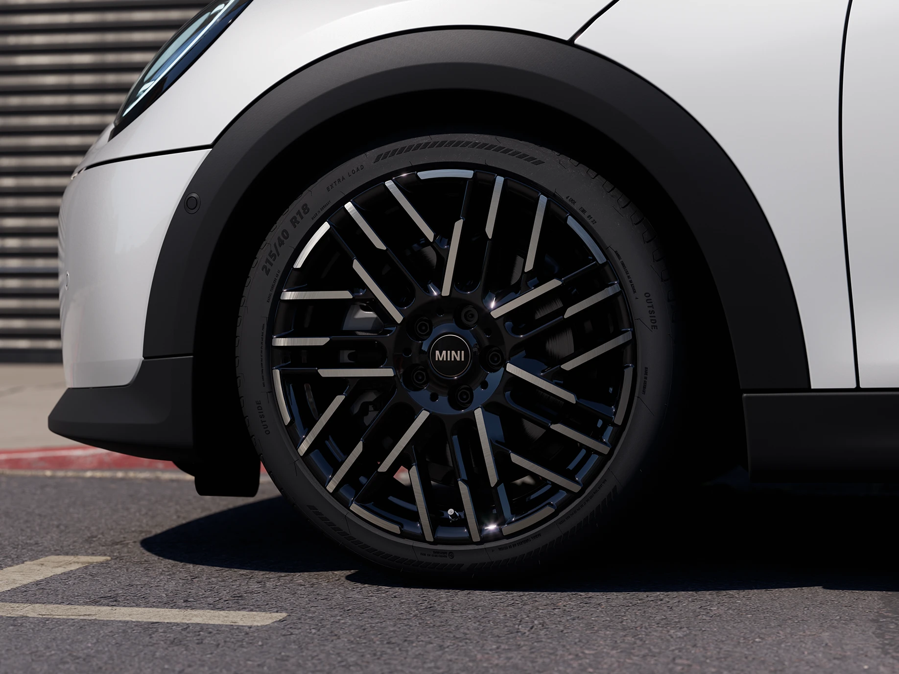Zbliżenie na 5-drzwiowe MINI Cooper w kolorze Nanuq White z 2-kolorowymi obręczami kół Night Flash Spoke.