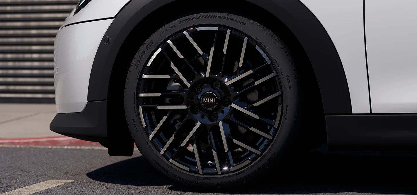 Zbliżenie na 5-drzwiowe MINI Cooper w kolorze Nanuq White z 2-kolorowymi obręczami kół Night Flash Spoke.