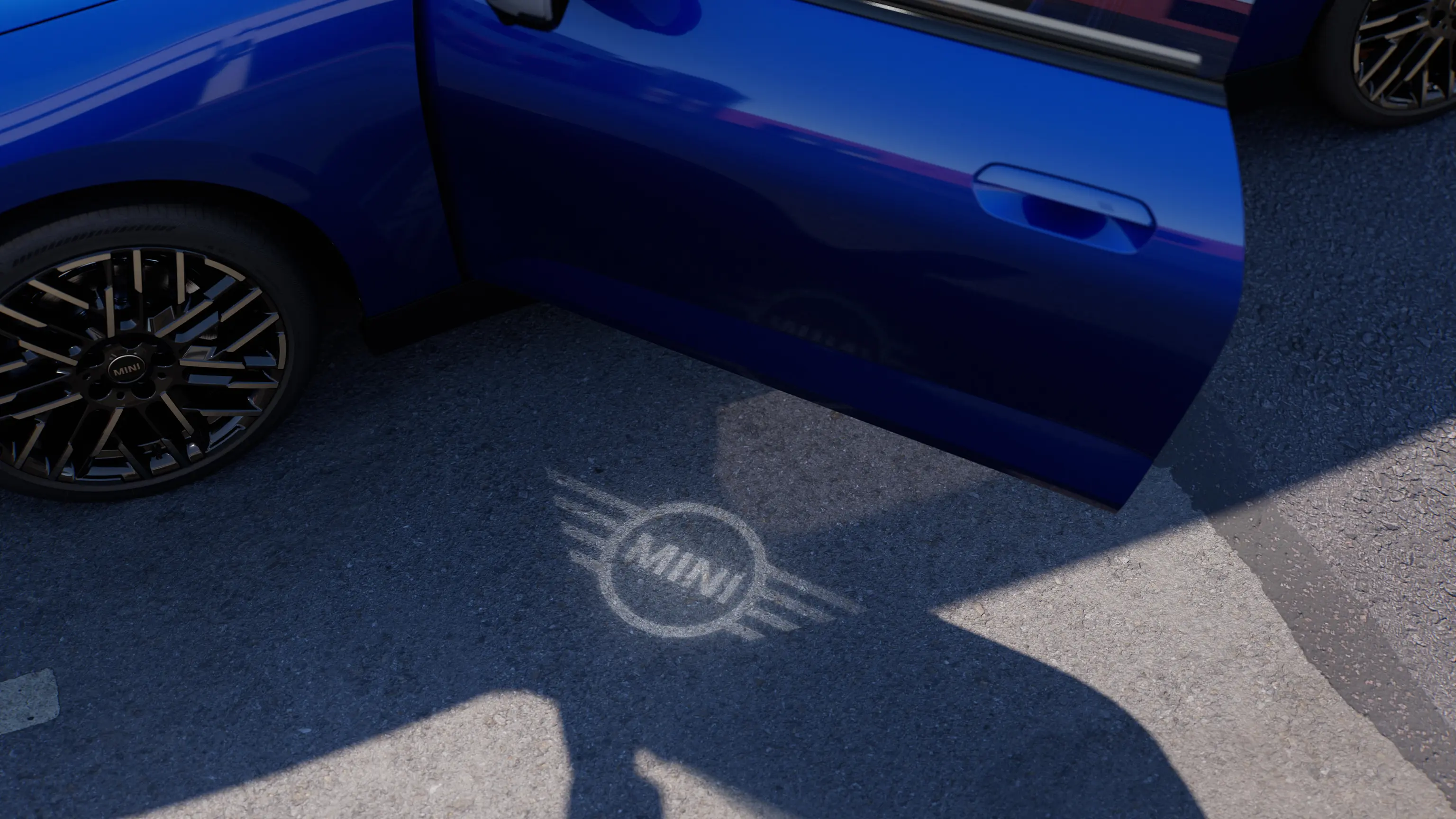 Widok z zewnątrz w pełni elektrycznego MINI Cooper z otwartymi drzwiami i logo MINI świecącym na ziemi