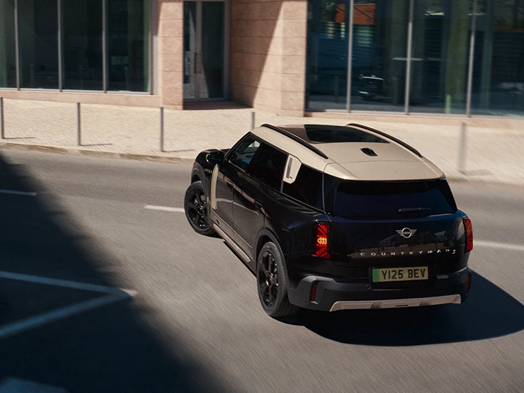 Widok z tyłu z góry na zaparkowane w pełni elektryczne MINI Countryman w kolorze Midnight Black z dachem w kolorze Vibrant Silver.