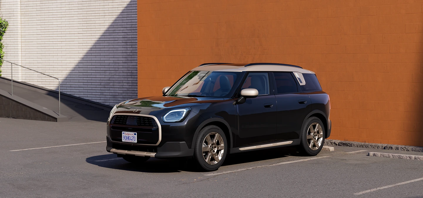 Widok z boku z przodu na zaparkowane MINI Countryman w kolorze Midnight Black z dachem w kolorze Vibrant Silver.