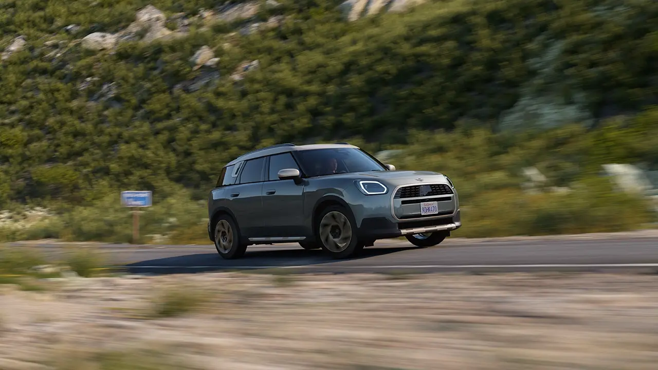 Widok MINI Countryman w kolorze Smokey Green w stylu Favoured podczas jazdy w terenie