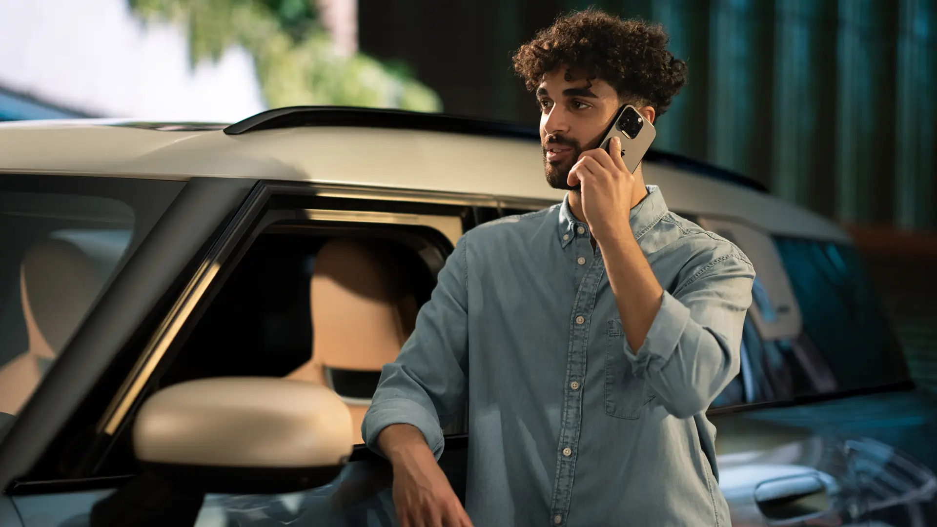 MINI Proactive Care – mężczyzna stoi z boku swojego MINI i rozmawia telefonicznie z konsultantem centrum obsługi klienta.