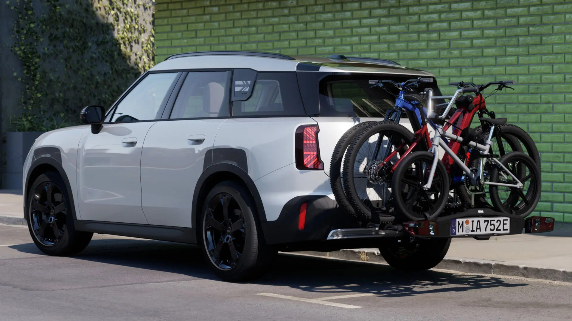 MINI Aceman w kolorze Nanuq White, wyposażony w tylny uchwyt rowerowy MINI Pro 3.0, przewożący dwa rowery górskie oraz rower dziecięcy.