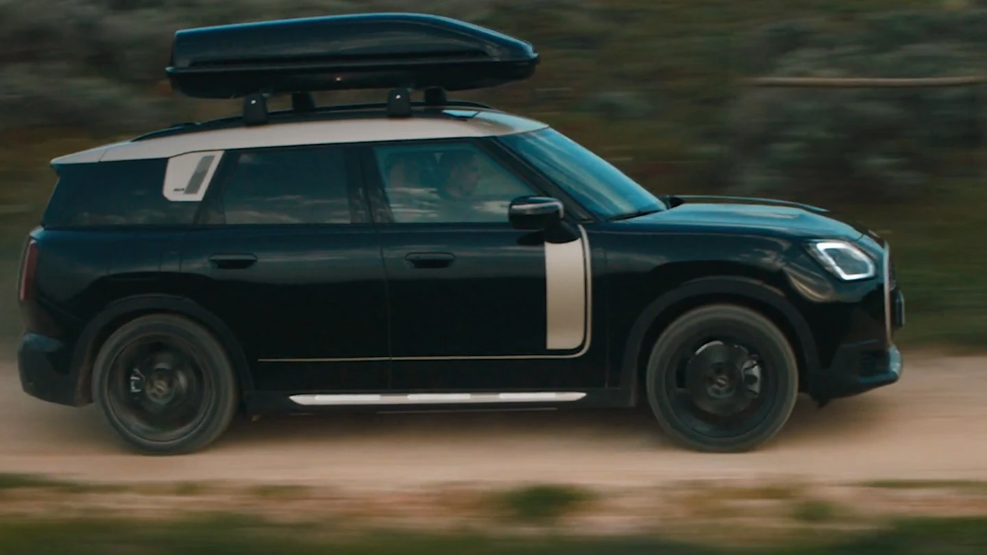 MINI Countryman w kolorze Midnight Black metallic z czarnymi 19-calowymi obręczami kół John Cooper Works Runway Spoke, jadący w terenie. 