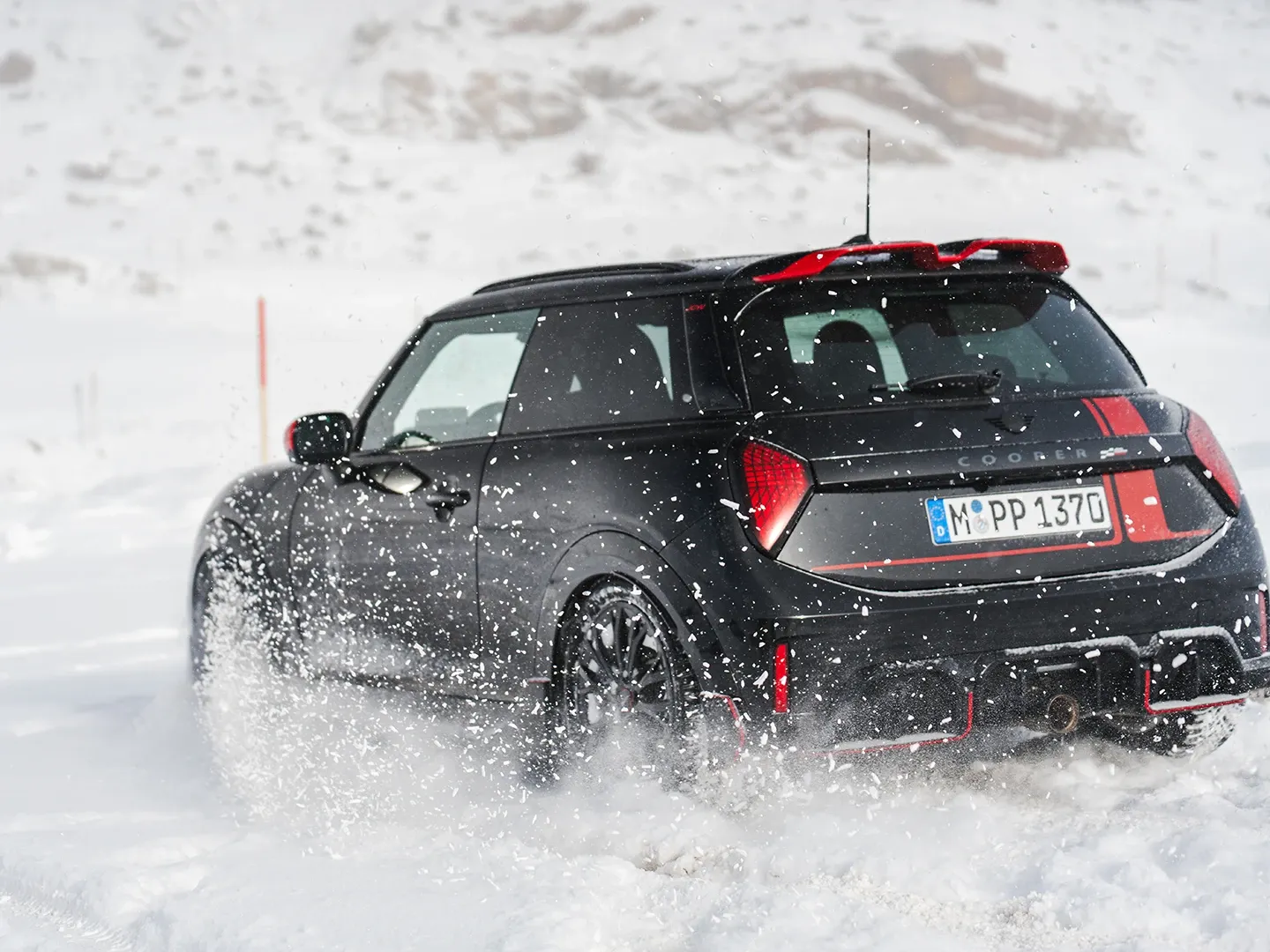 Widok z tyłu na MINI Cooper JCW podczas jazdy po śniegu.