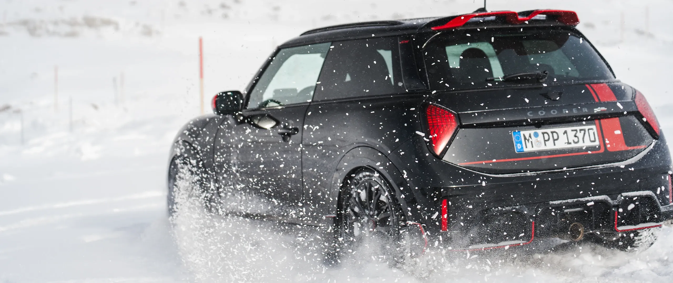 Widok z tyłu na MINI Cooper JCW podczas jazdy po śniegu.