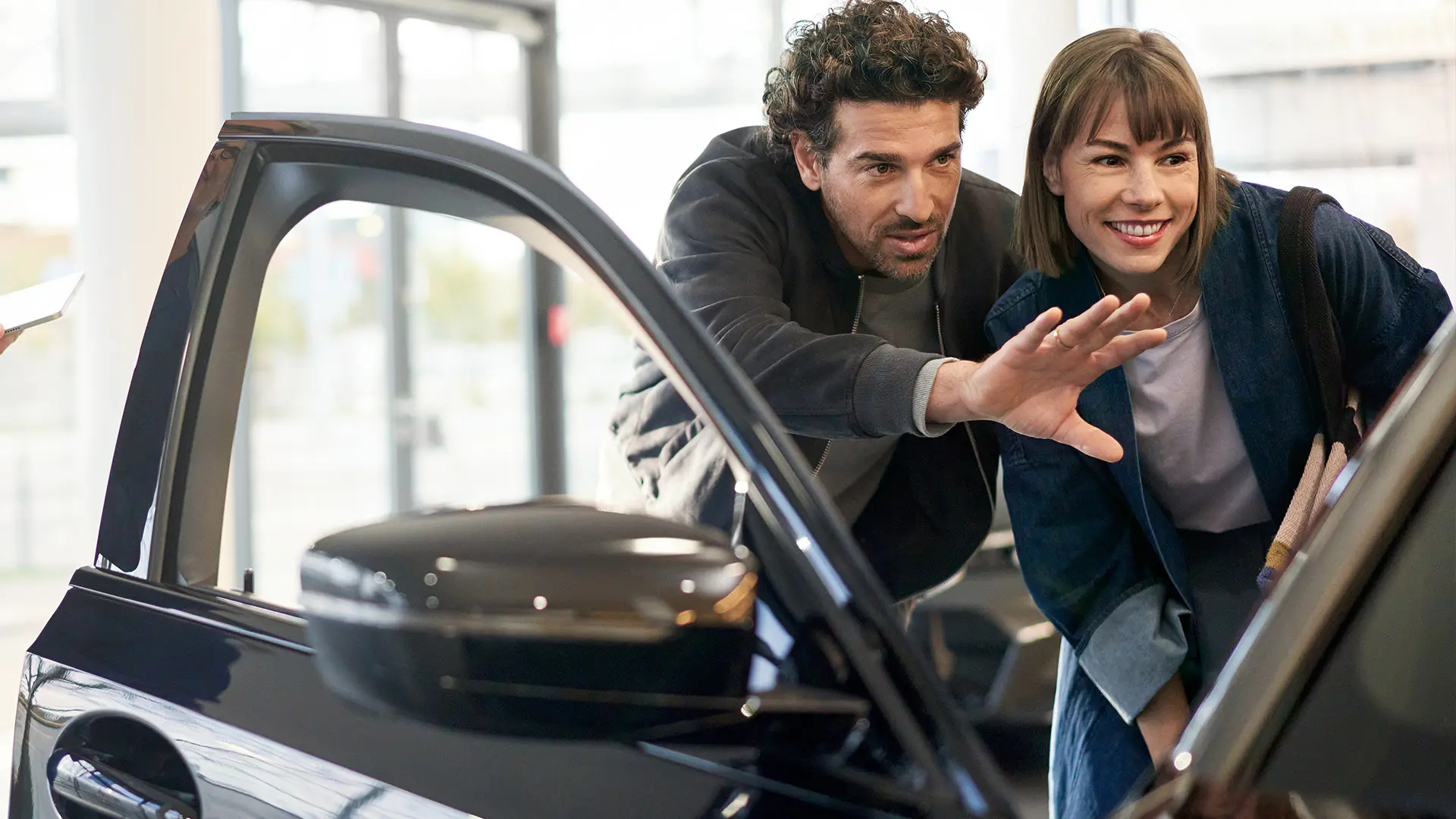 MINI stojące w salonie dealerskim MINI, konsultant doradzający klientowi i wyjaśniający funkcje kabiny pojazdu.