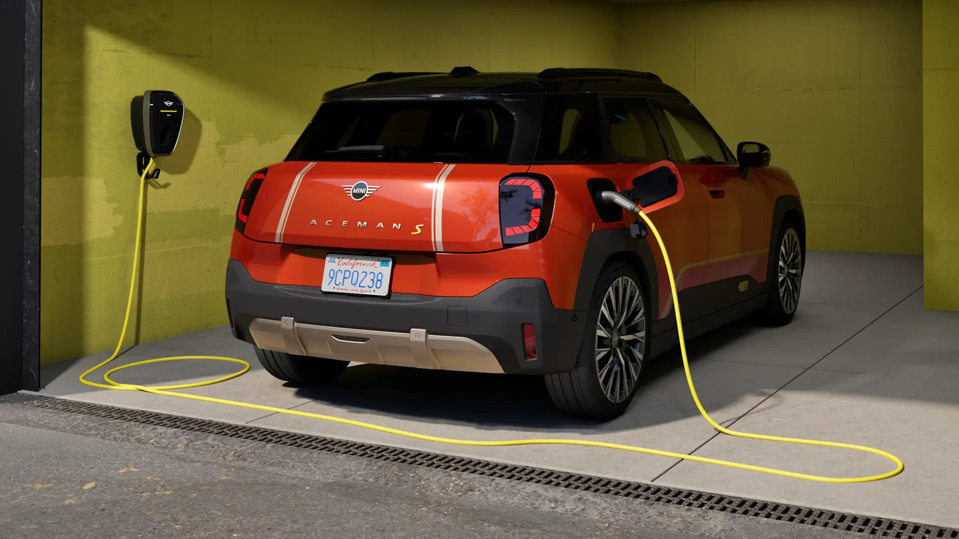 W pełni elektryczne MINI Aceman S ładowane za pomocą stacji ładowania MINI Wallbox Plus, widziane z tyłu, zaparkowane w garażu.