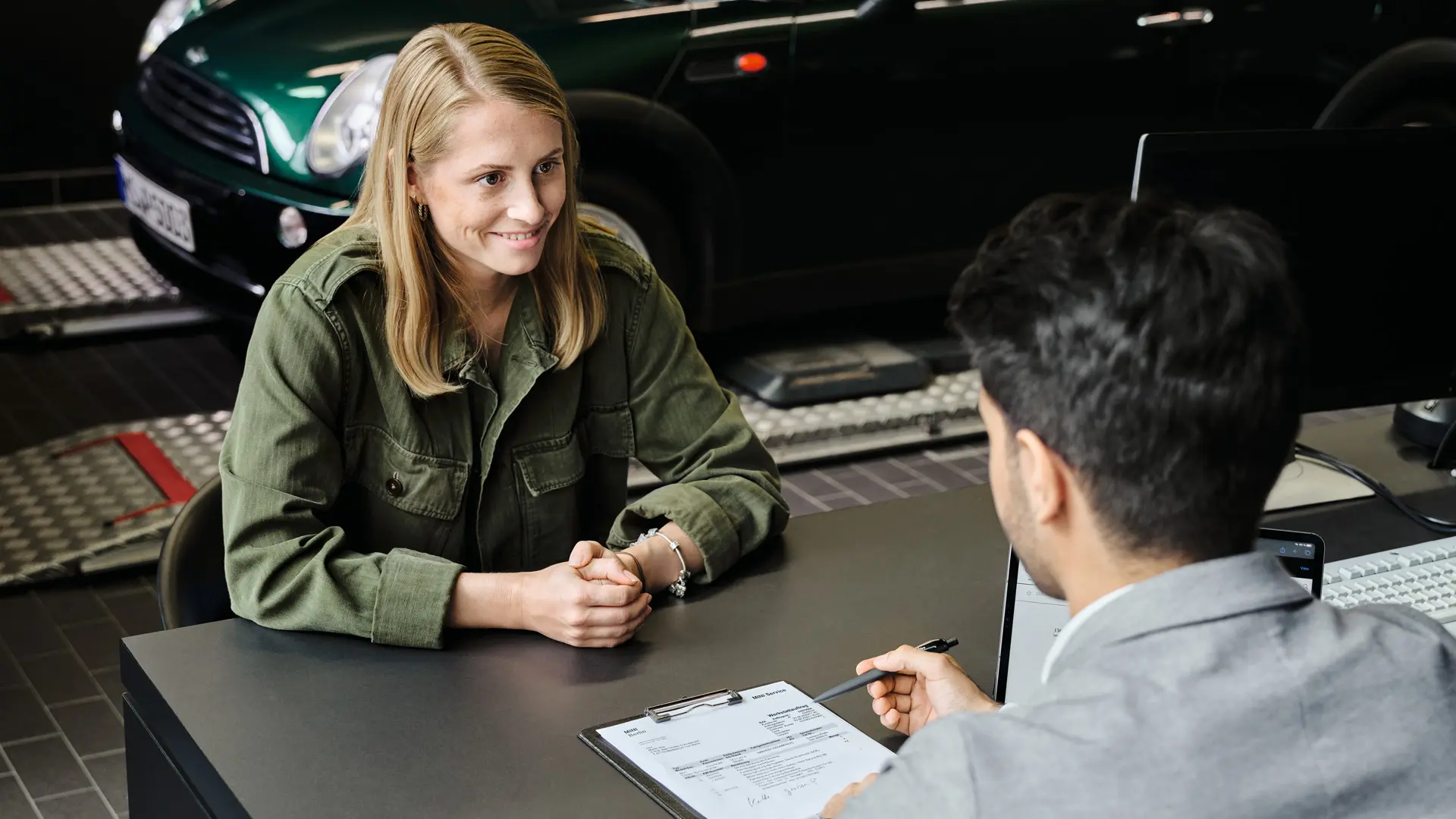 Salon MINI z konsultantem doradzającym klientce w zakresie opcji serwisowych, oboje siedzą przy stoliku.