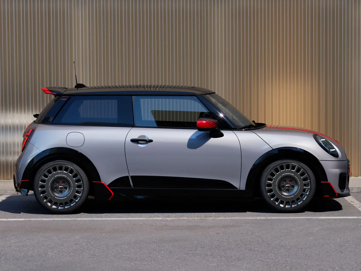3-drzwiowe MINI Cooper w kolorze Melting Silver ze spojlerem tylnym John Cooper Works, zapewniającym lepsze właściwości aerodynamiczne – widok z boku.